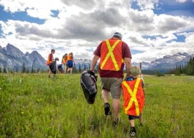 2022 David Thompson Corridor Cleanup Family walking thoruhg the grass picking garbage